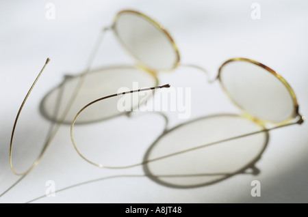 Une paire de lunettes avec lentilles circulaires et fine écaille de frames et le fil d'un grand casting d'armes ombre complexes Banque D'Images