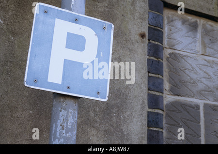 P bleu et blanc ou Parking sign sur un poteau ou un lampadaire par un ciment terne et breeze block wall Banque D'Images