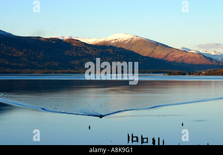 Un petit bateau quitte Service avec des montagnes derrière sur le Loch Lomond Ecosse Banque D'Images