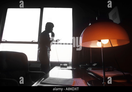 Conseil exécutif man on telephone in office silhouetted against window Banque D'Images