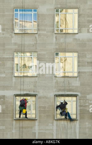 Close up portrait of Vertical de deux laveurs de vitres suspendu de cordes en haut d'un immeuble de bureaux. Banque D'Images