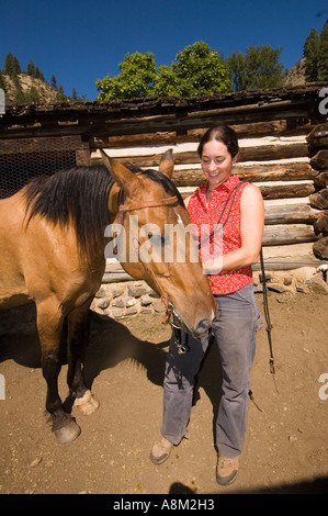 California Indian Creek Guest Ranch Dame wrangler prêt à selle son cheval près de la rivière Salmon et M. Shoupe Banque D'Images
