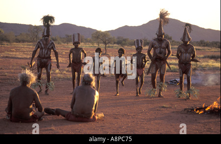 Les aînés autochtones, les jeunes garçons de l'enseignement et l'entreprise cérémonie danse rituelle au coucher du soleil dans le désert de l'Australie centrale à distance Banque D'Images
