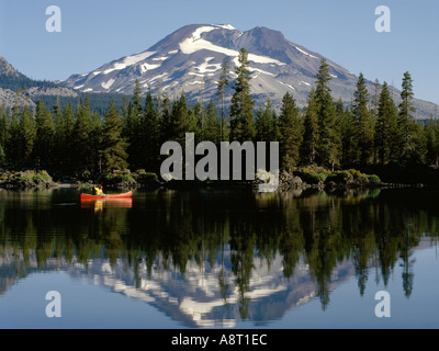 Pêcheur dans red canoe sur le paisible lac d'eaux réfléchissantes des étincelles avec Sœur du Sud montagne dans la chaîne des Cascades en Oregon Banque D'Images