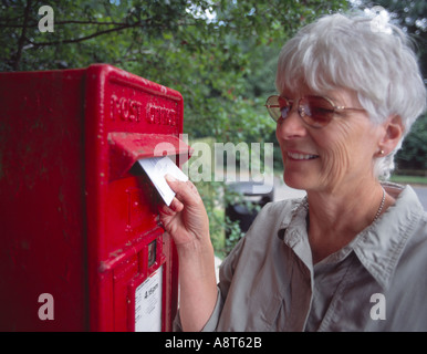 Femme âgée poster une lettre en rouge traditionnelle lettre britannique fort dans le pays Banque D'Images