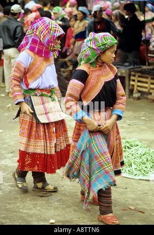 Deux jeunes habillés traditionnellement les femmes Hmong Fleur marche à travers le marché du dimanche, Bac Ha, NW Viet Nam Banque D'Images