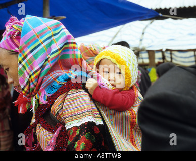 Habillé traditionnellement femme Flower Hmong avec bébé dans un marché porteur, samedi, peuvent cau, NW Viet Nam Banque D'Images