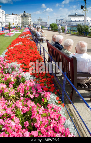 Quatre retraités le soleil brille sur la promenade à Eastbourne, Sussex, Angleterre, Royaume-Uni. Banque D'Images