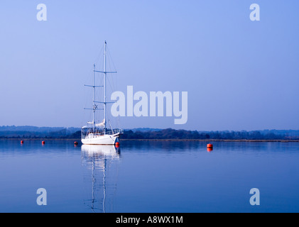 Yacht blanc et bouées rouges sur l'eau calme. Le port de Poole. Dorset UK . Banque D'Images