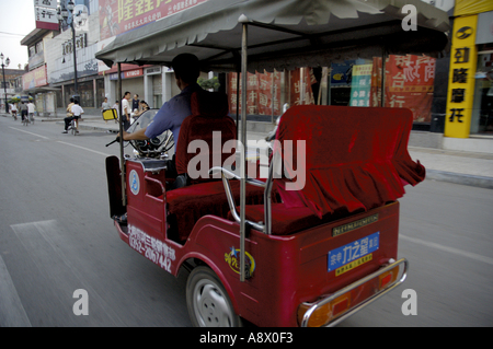 Tricycle rouge roulant sur un boulevard, Datong, Shanxi, en Chine. Banque D'Images