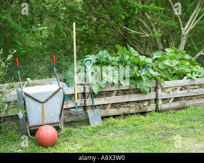 Compost recyclage organique avec des courgettes à la suite des outils de jardin haut et brouette Banque D'Images