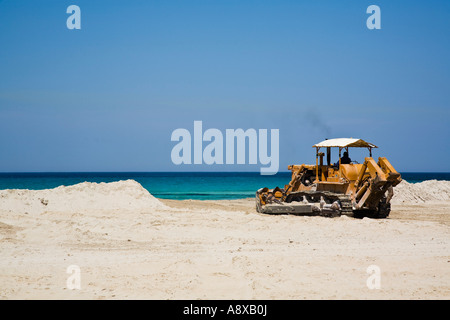 Le déplacement du tracteur Caterpillar sable sur plage sur la mer Tyrrhénienne à San Vito Lo Capo Sicile Italie Banque D'Images