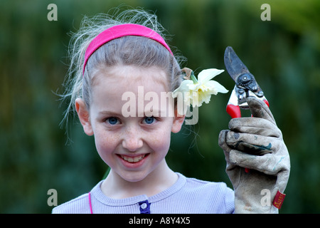 Jeune fille peu attrayant est titulaire d'un sécateur. Aider dans un jardin de campagne anglaise. Banque D'Images