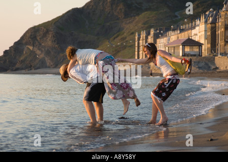 Trois jeunes hommes et deux jeunes filles, jouant en bord de mer promenade Aberystwyth soir d'été, les étudiants universitaires Banque D'Images