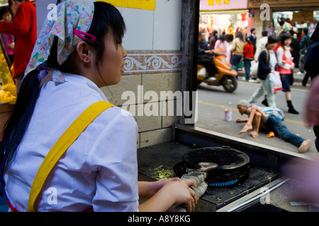 La friture d'aliments de rue Femme Homme sans foyer en faisant glisser le long de lui-même à l'extérieur de la Chine Guangzhou Banque D'Images