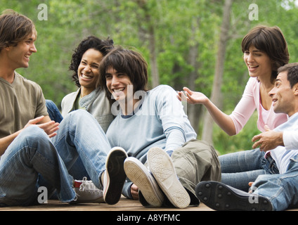 Groupe de jeunes amis assis autour de concert en plein air, rire Banque D'Images