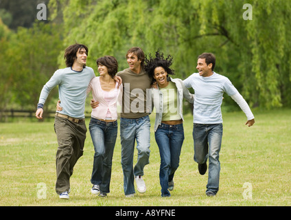 Groupe de jeunes amis avec les bras autour de l'autre, sauter dans les champs Banque D'Images