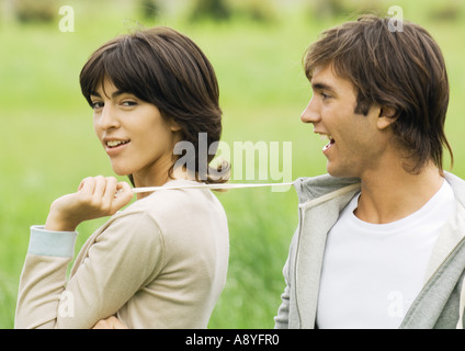 Young couple outdoors, woman pulling string sur l'homme noir Banque D'Images