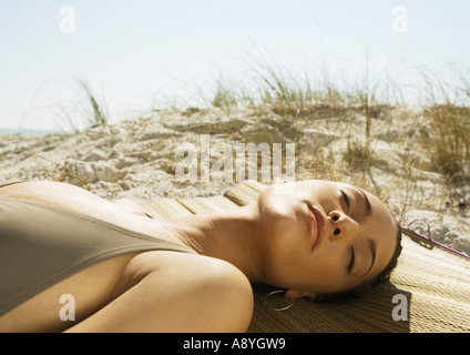 Woman lying on beach, sand dune in background Banque D'Images