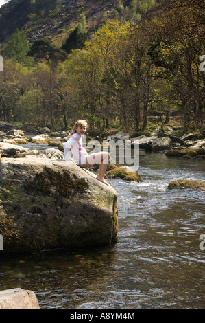 Jeune fille blonde jouant dans la rivière Glaslyn en aval du parc national Snowdonia Beddgelert Gwynedd au nord du Pays de Galles printemps Banque D'Images