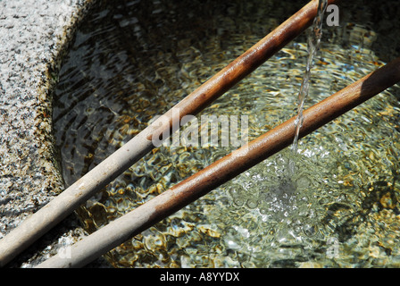 Un ruisseau d'eau claire tombe dans un bassin en pierre ronde au Temple Kiyomizu, Kyoto. Banque D'Images