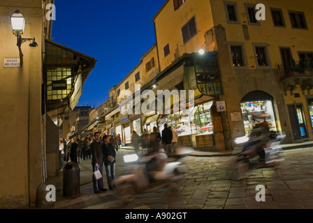 Grand angle horizontal de gens qui marchent le long de l'animation de la Ponte Vecchio de nuit. Banque D'Images