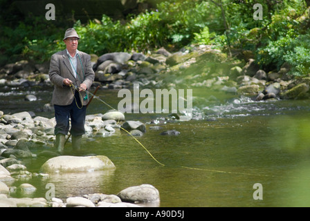 Un vieux gentleman anglais à la retraite la pêche à la mouche sur une rivière forestiers dans le nord-ouest de l'angleterre Banque D'Images