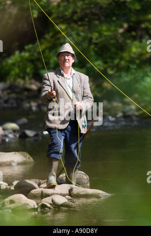 Un vieux gentleman anglais à la retraite la pêche à la mouche sur une rivière forestiers dans le nord-ouest de l'angleterre Banque D'Images