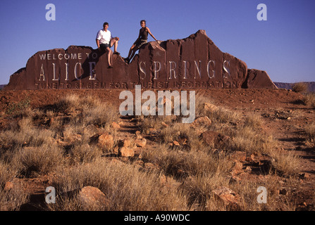 Deux adultes assis sur Bienvenue sur Alice Springs Rock, Territoire du Nord, Australie Banque D'Images