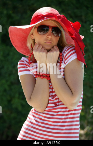 Fille blonde portant un chapeau et robe rayée rouge et blanc Banque D'Images