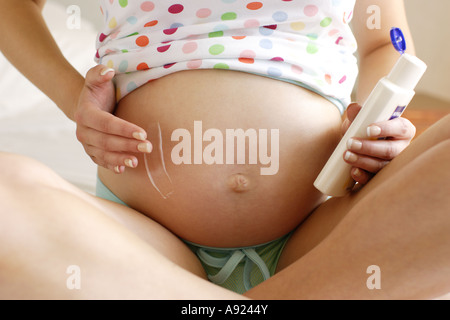 Femme enceinte ventre hydratant Banque D'Images