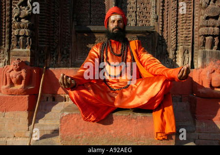 Saint homme necklesses avec de nombreux sadhu habillé en robe orange brillant est assis en face d'un temple Katmandou Népal Banque D'Images