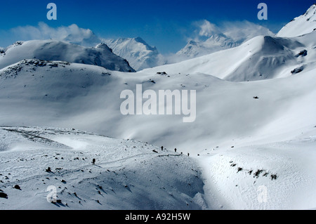 Certains randonneurs sur leur façon de Thorung La Pass par l'intermédiaire de très hautes montagnes enneigées de la région de l'Annapurna au Népal Banque D'Images