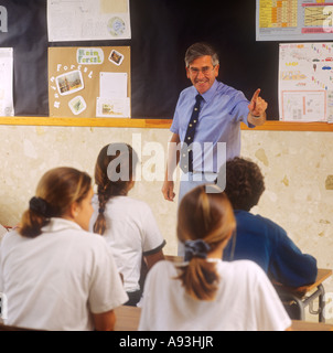 Professeur pointant vers l'adolescent dans la classe d'école de senior avec tableau noir et dos des chefs d'élèves 15-17 ans dans uniforme scolaire Banque D'Images