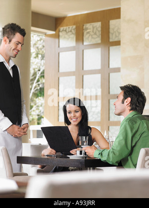 Couple de commande auprès de serveur au restaurant en plein air Banque D'Images