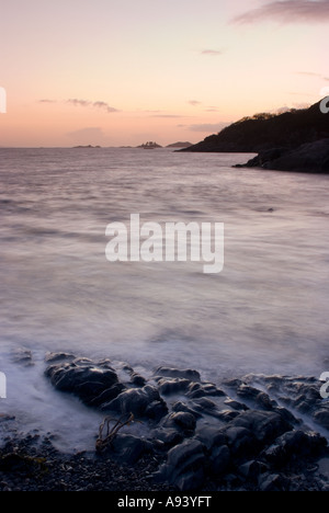 Misty waves crash sur une plage de galets, rochers au coucher du soleil de la création de l'Écosse l'imagerie mystique eery Banque D'Images