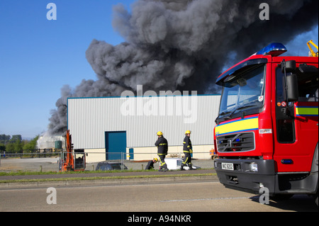 Cabine de camion d'incendie avec des pompiers à l'extérieur et en arrière-plan sous colonne de fumée à l'incendie à l'entrepôt médical coleraine Banque D'Images