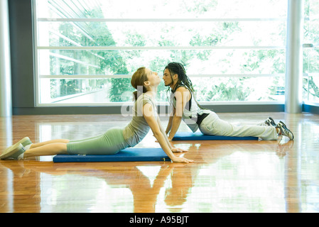 Deux jeunes adultes faisant poser cobra in yoga studio Banque D'Images