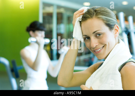 Femme en salle de poids, l'essuyant le front, smiling at camera Banque D'Images