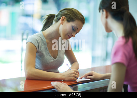 Jeune femme en signature au comptoir du club de santé Banque D'Images