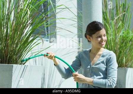 Jeune femme d'arroser les plantes de plein air avec flexible Banque D'Images