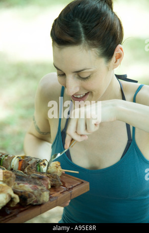 Woman picking up kebab grillé Banque D'Images