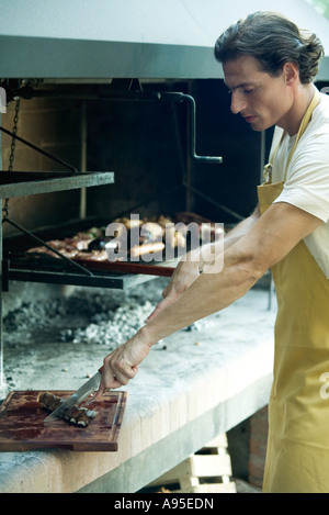 Man barbecuing, morceau de viande de coupe Banque D'Images