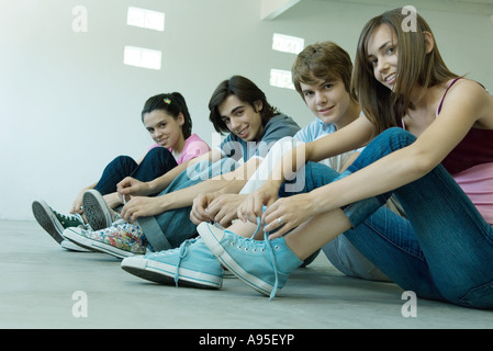 Amis adolescents portant des chaussures en toile, lacets de liage Banque D'Images