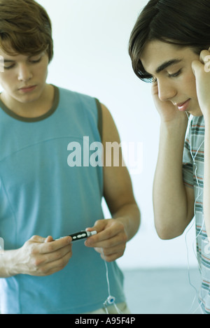 Teenage boys listening to MP3 player Banque D'Images