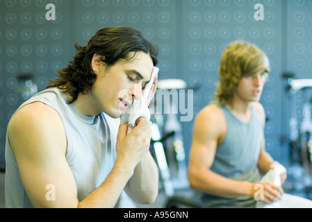 Les hommes dans la salle de gym, un visage d'essuyage Banque D'Images