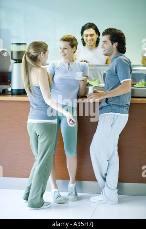 Les jeunes adultes habillés en vêtements d'exercice, debout près d'un snack-bar, le chat Banque D'Images