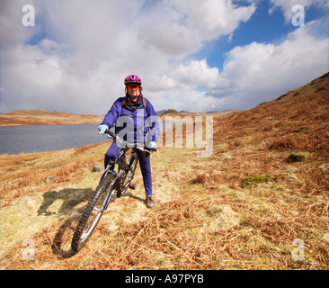 Vélo de montagne femelle sur les rives de l'eau, l'Devoke Cumbria Banque D'Images