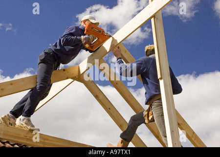 Contructing bâtisseurs d'un nouveau toit pour une extension d'une maison à l'aide d'un pistolet de scellement Banque D'Images