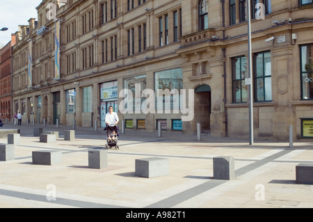 Homme marchant dans le centre-ville de Manchester en poussant la pram Banque D'Images